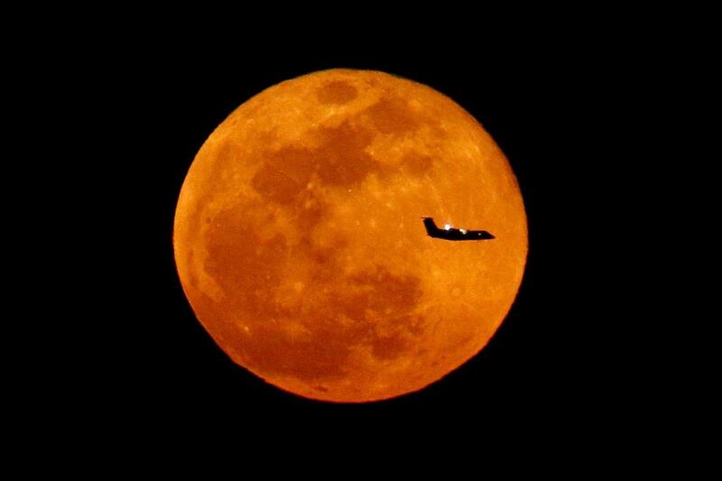 A plane descending into Newark Liberty International Airport crosses over the full moon rising seen from Eagle Rock Reservation in West Orange, N.J. Julio Cortez / AP Photo