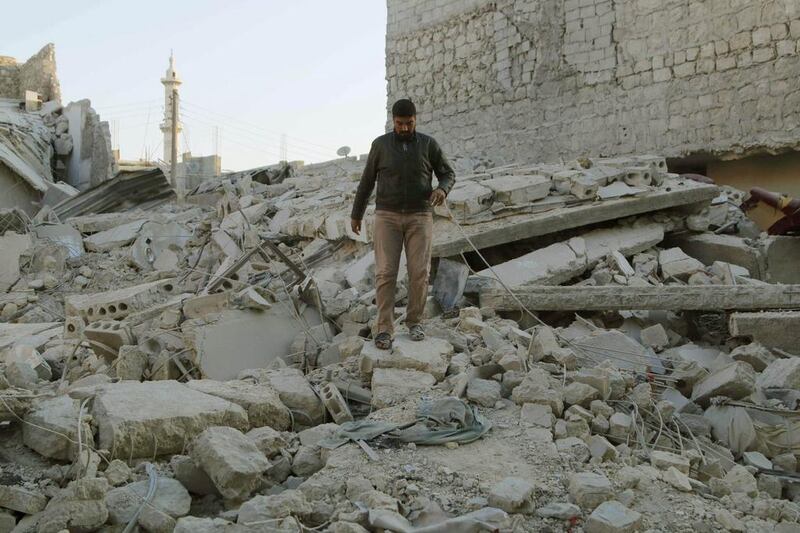A man walks over rubble after barrel bombs were dropped by forces loyal to Syrian president Bashar Al Assad in Aleppo's Al Haidariya neighbourhood on Saturday. Hosam Katan / Reuters