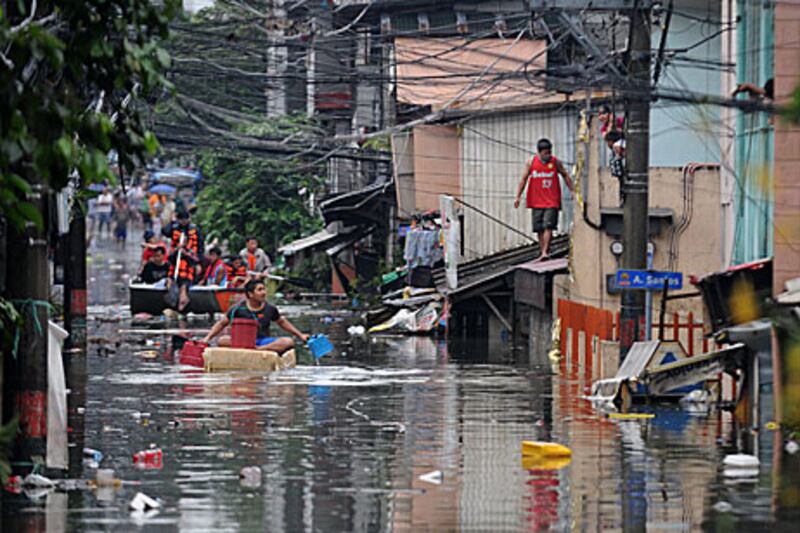 A man floats down a flooded street in Manila today.