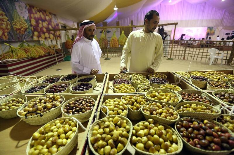 Suhail Mohammed, left, and Hisham Ali look over some of the prize-winning dates at the Liwa Date Festival last year. Sammy Dallal / The National 