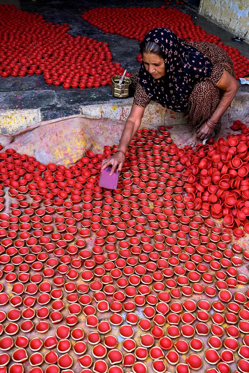 A craftswoman paints diyas or earthen oil lamps in Amritsar. AFP