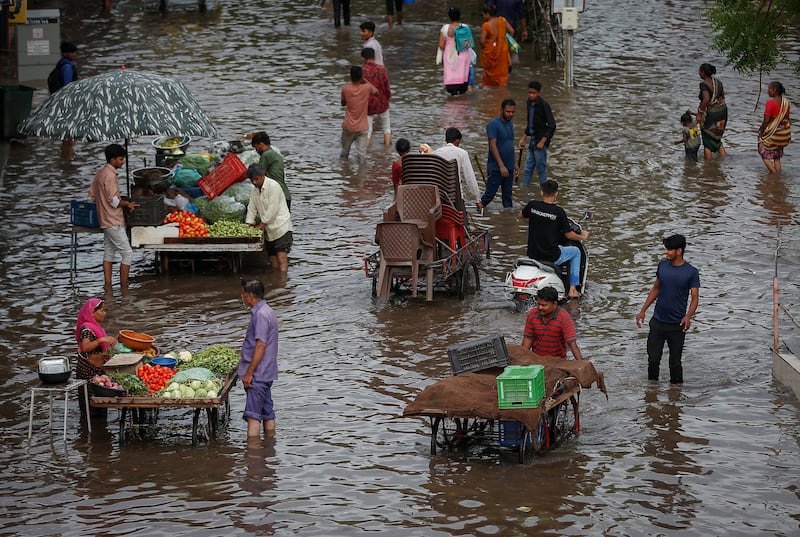 Street vendors sell vegetables amid flooding on Monday following heavy rains in Ahmedabad, India. Reuters