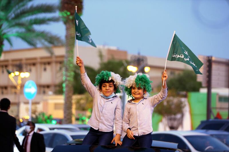Children wave flags as people celebrate Saudi Arabia's 90th annual National Day in the capital Riyadh in 2020. Reuters
