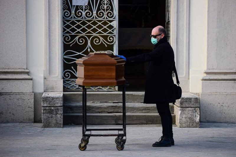 A man touches the coffin of his mother during a funeral service in the closed cemetery of Seriate, near Bergamo, Lombardy during the country's lockdown aimed at stopping the spread of the COVID-19 (new coronavirus) pandemic.   AFP