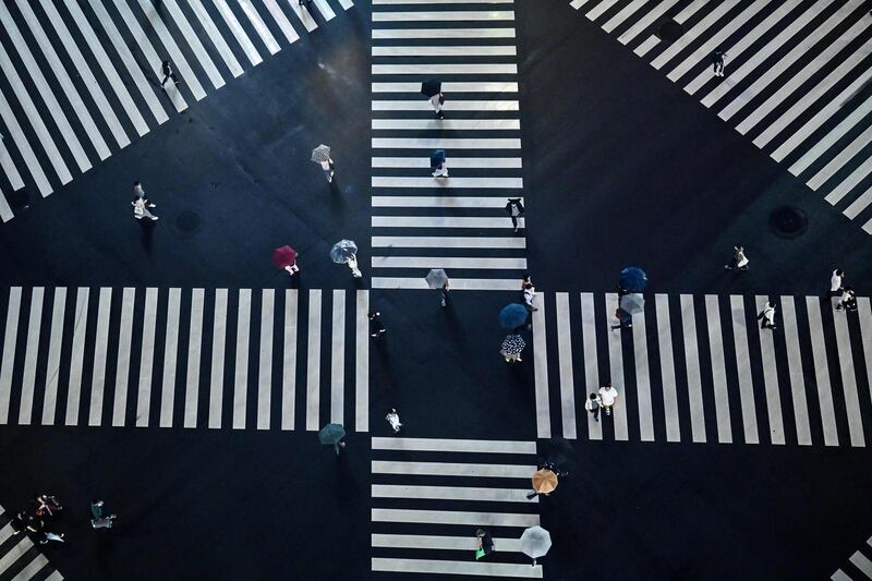 Pedestrians cross a street during a rainy evening in Tokyo. AFP