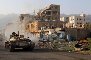 Yemeni fighters loyal to President Abdrabu Mansur Hadi ​​ride a tank past a destroyed building during clashes with Houthi rebels in the country’s third city of Taez on May 30. AFP