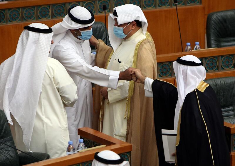 Kuwaiti MPs wearing protective masks greet each other at the start of a parliamentary session at the National Assembly in Kuwait City. AFP