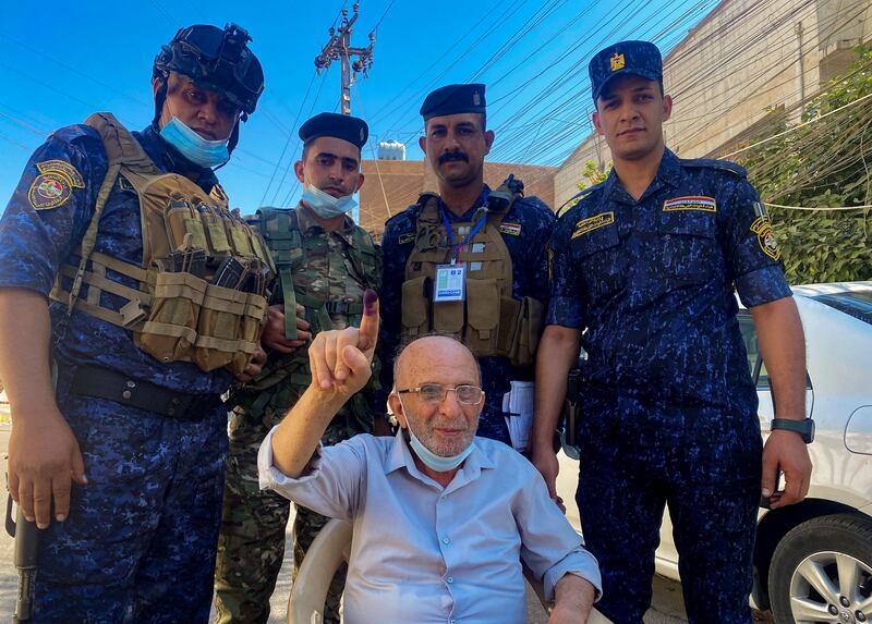 Iraqi security forces pose for a photo with an elderly man after he cast his vote in Baghdad. Photo: Reuters