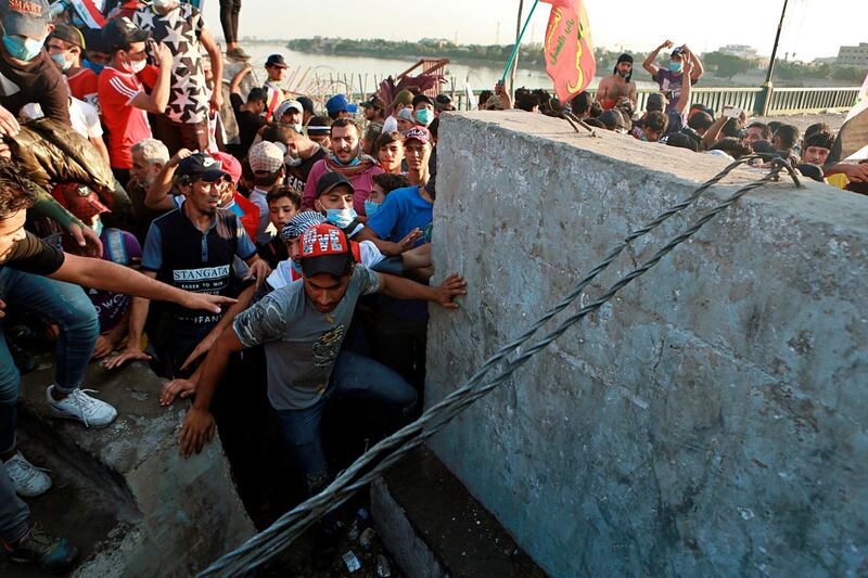 Anti-government protesters pull down concrete walls on a bridge leading to the Green Zone during a demonstration in Baghdad, Iraq. AP Photo