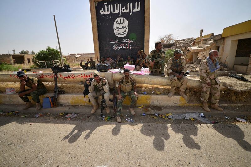 Shi'ite Popular Mobilization Forces (PMF) sit next to the black flag sign commonly used by Islamic State militants, after liberating the city Hawija, Iraq, October 5, 2017. REUTERS/Stringer NO RESALES. NO ARCHIVES     TPX IMAGES OF THE DAY