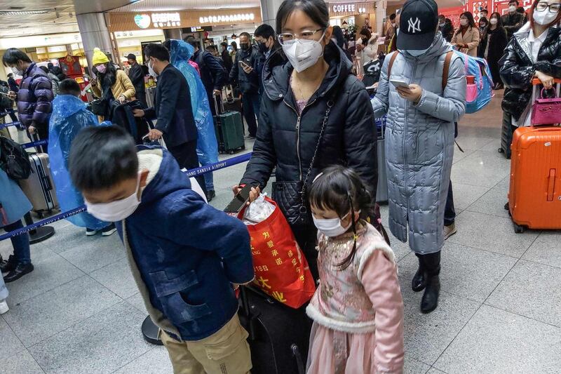 Passengers wearing face masks, amid concerns of the COVID-19 coronavirus, queueing up to check-in before boarding flights at Yichang Sanxia Airport in Yichang in China's central Hubei province.  AFP