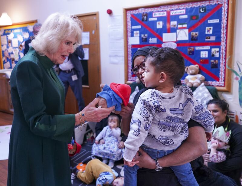 Camilla, Queen Consort hands a Paddington Bear toy to a child during a teddy bears' picnic at a Barnardo's Nursery in Bow, east London. PA