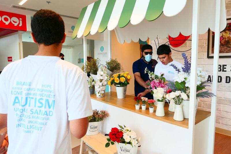 Omar Al Suwaidan (right) at the flower shop at the Sanad village mall in Dubai Sustainable City on April 29,2021. This centre is for people of determination fit out with real simulation zones like malls, clinics and an airport to help students gain independence. Pawan Singh / The National. Story by Kelly