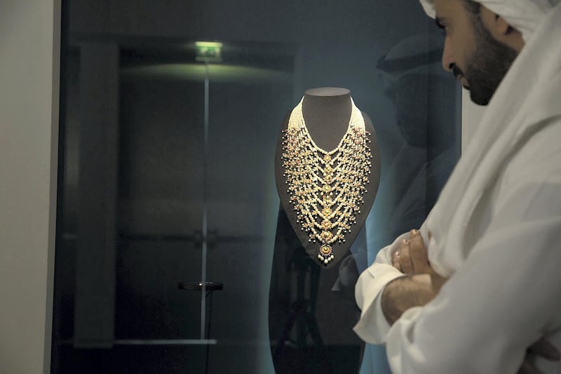 A visitor to '10,000 Years of Luxury' looks at an antique necklace featuring Gulf pearls. Courtesy of the Department of Culture and Tourism – Abu Dhabi. Photo by Ismail Noor