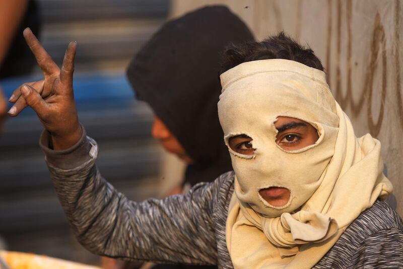 An Iraqi boy wearing a makeshift mask flashes the victory gesture during clashes between anti-government protesters and security forces in the Iraqi capital Baghdad's Rasheed street near al-Ahrar bridge. AFP