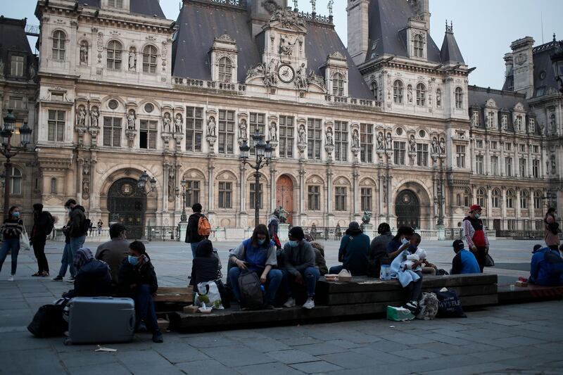 Parisians and homeless gather in front of Paris city hall, one hour after the 19h00 curfew, in Paris. France's prime minister Jean Castex on Thursday defended new nationwide measures to combat a resurgent coronavirus in France that include closing schools for at least three weeks and putting in place a month-long domestic travel ban, the government has acted "consistently and pragmatically". AP Photo