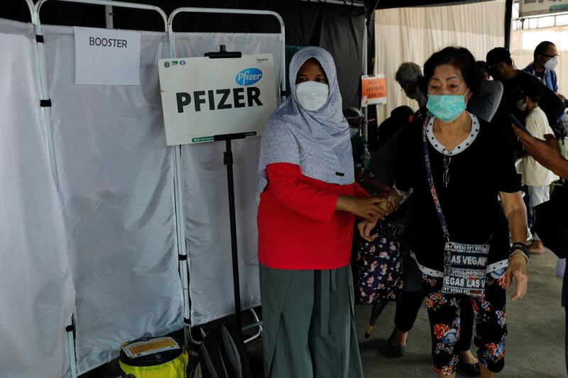 An elderly woman is helped after receiving a booster dose of the Pfizer vaccine in Jakarta, Indonesia. Reuters