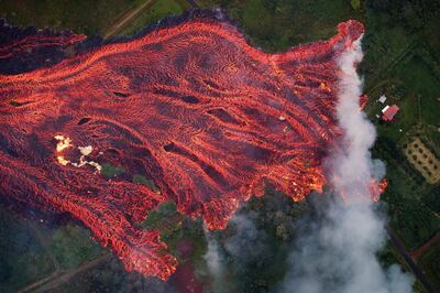epaselect epa06750791 A massive fast moving lava flow consumes everything in its path, as the flames from the remnants of one home burns on the left, while it approaches another on the right.   Pahoa, Hawaii, USA, 19 May 2018. The ongoing eruption of Kilauea is the largest in decades, destroying more than 40 homes to date, and displacing thousands.  EPA/Bruce Omori/Paradise Helicopters
