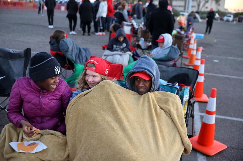 Mark Swindell (R) and his daughters Ivy (L) and Ella try to keep warm at dawn while waiting in line to attend a campaign rally with U.S. President Donald Trump at Phoenix Goodyear Airport n Goodyear, Arizona.  AFP