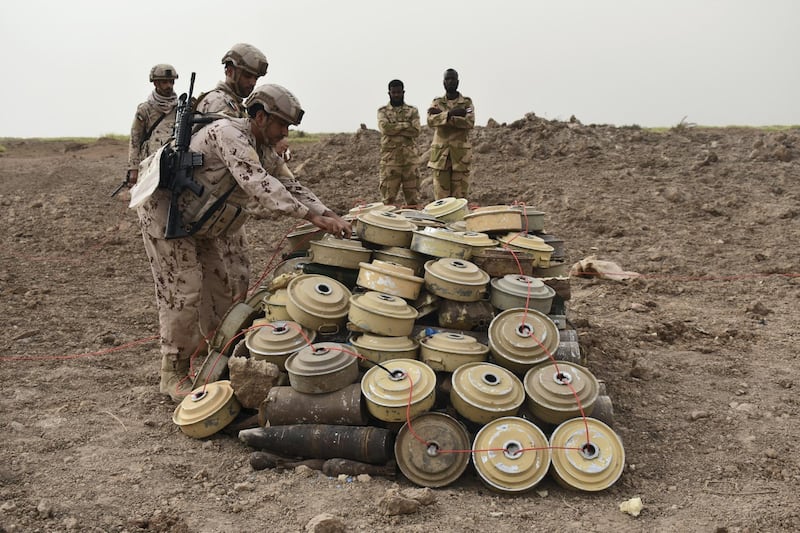 UAE minesweepers lay ignition cord across a cache of Houthi landmines, as two Sudanese colleagues look on. Gareth Browne / The National