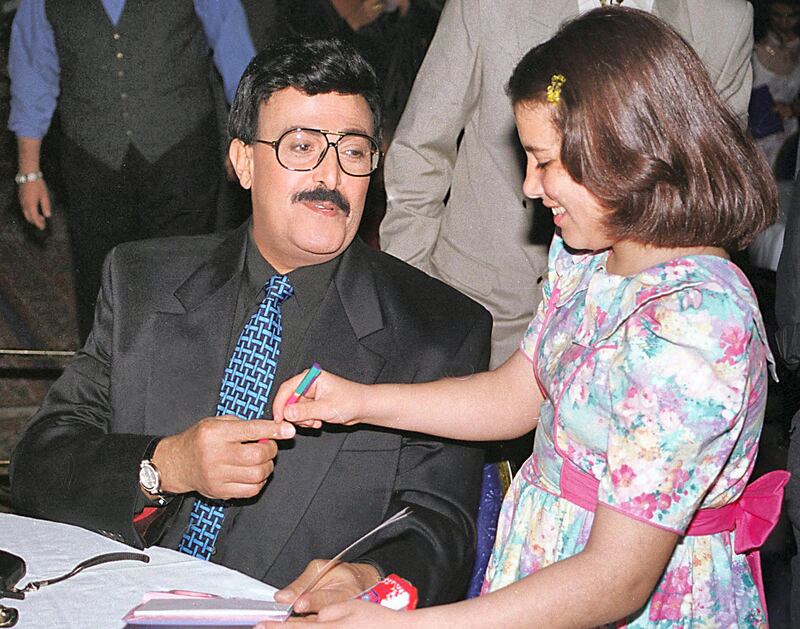 Egyptain comedian Samir Ghanem signs an autograph to a child at Cairo's Zamalek Club late 03 May 2000. Ghanem was honored by the club for his three-decade achievements in film and television comedy and entertainment. (Photo by AMR MAHMOUD / AFP)