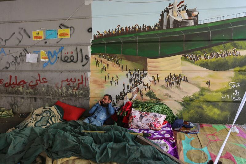 An Iraqi protester rests in front of a mural at Baghdad's Tahrir Square. AFP