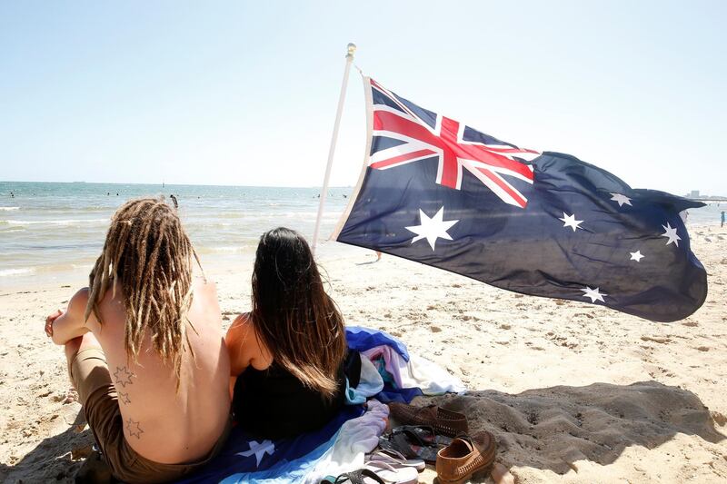 A couple enjoy the sun on St Kilda beach on Australia Day. Getty