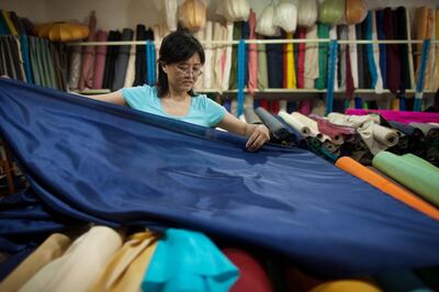 A vendor prepares rolls of silk at her textile and fabric shop in Beijing on July 19, 2012. China should keep up reforms as it tries to steer its slowing economy to a soft landing, a senior US Treasury official said July 18. AFP PHOTO / Ed Jones / AFP PHOTO / Ed Jones