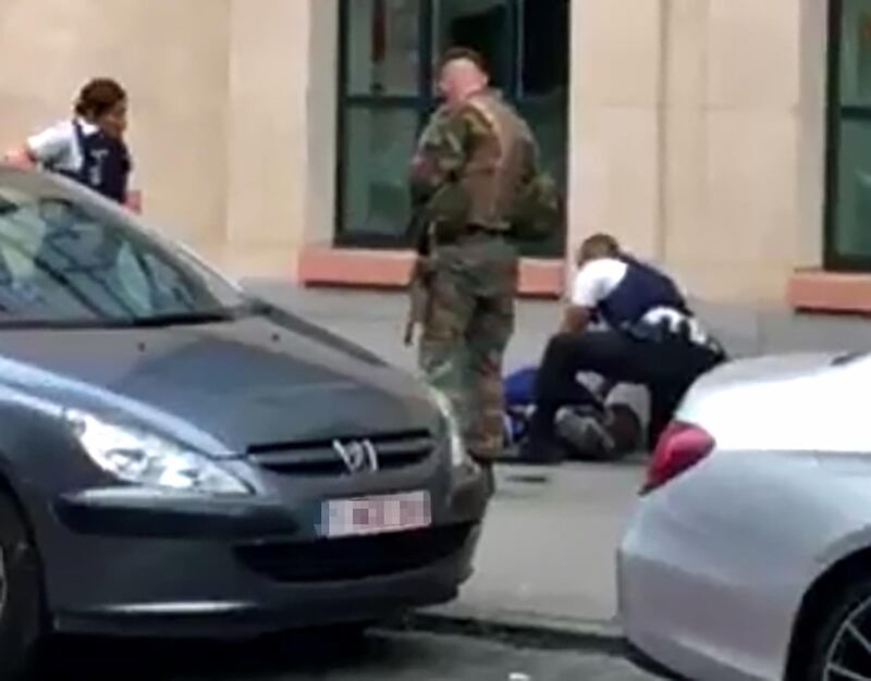 This screengrab shows police officials and a soldier looking at a man on the pavement in the city centre of Brussels on August 25, 2017, where a man is alleged to have attacked soldiers with a knife and was shot.
 / AFP PHOTO / Belga / STR / Belgium OUT
