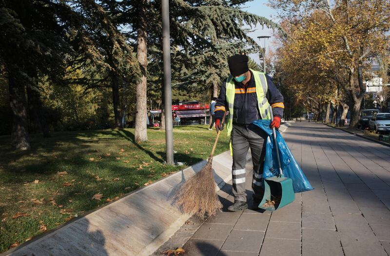 A city worker wearing mask to help protect against the spread of coronavirus, cleans a sidewalk, in Ankara, Turkey.  AP Photo