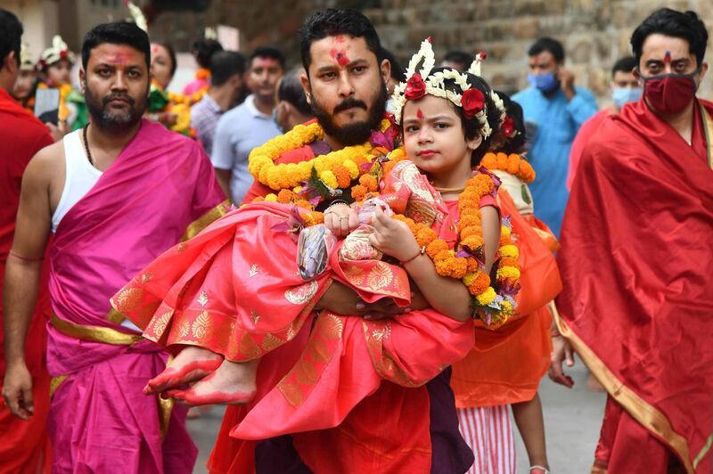 A devotee carries a girl dressed as a Hindu goddess during the Durga Puja festival at the Kamakhya temple in Guwahati, India. AFP