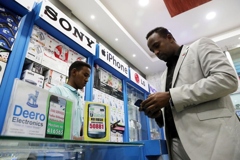 HARGEISA , SOMALILAND,  October 11 , 2018 :- Abdinasir Ahmed Hersi ( right ) buying mobile phone after using mobile payment services at the Deero Electronics shop at the Deero Mall in Hargeisa city in Somaliland. Most of the people using Zaad and EDahab mobile payment services which is on display for the customers to buy items. ( Pawan Singh / The National )  For News. Story by Charlie