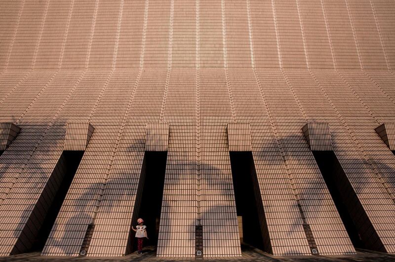 A child stands between the pillars of the Cultural Centre on the Kowloon side of Hong Kong. Isaac Lawrence / AFP Photo