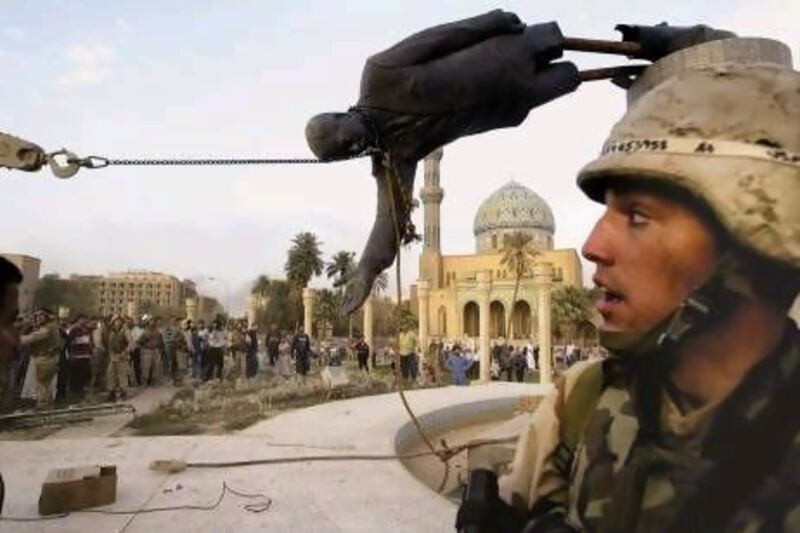 Iraqi civilians and US soldiers watch the statue of Saddam Hussein being pulled down in Baghdad on April 9, 2003.