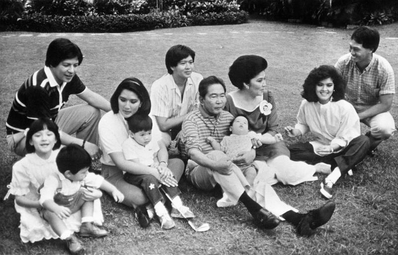 Philippines President Ferdinand Marcos (C) poses with the members of his family ; his wife Imelda (3-R), eldest daughter Imee and her husband Tomas Manotoc (R), youngest daughter Irene and her husband Greggy Araneta (next to the president at left), his son Ferdinand Jr. (behind the President), his grandchildren Luis (in president's lap), Alfonso (Irene's lap) and Borgy (left), being carried by the first couple's ward Aimee, on January 15, 1986. AFP PHOTO (Photo by PALACE HO / AFP)