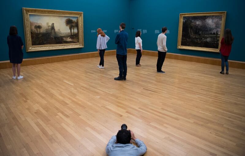 epa06761925 A photographer makes an image of workers posing with British artists JMW Turner's Caligula's Palace and Bridge (L) John Constable's Salisbury Cathedral in the Meadow (R) (both 1831) during a photo-call for the exhibition Fire and Water a display of Constable and Turner at Tate Britain in London, Britain, 25 May 2018. Fire and Water brings John Constable's painting Salisbury Cathedral in the Meadow and JMW Turner's Caligula's Palace and Bridge both (1831) on display for the first time in 180 yers. The display opens to the public on 26th May 2018 at Tate Britain.  EPA/NEIL HALL