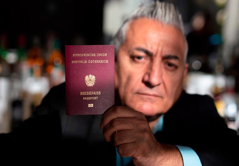 Alper Yilmaz poses with his Austrian passport at his cafe restaurant in Vienna, Austria, on October 31, 2018. Alper Yilmaz is in little doubt as to where he feels at home. "My homeland is Austria, Vienna," he says.
But with a far-right party sharing power and anti-immigration sentiment generally on the rise in Austria, an anxious Yilmaz is one of potentially thousands of Austrians with Turkish roots facing the possibility of losing their citizenship.
 / AFP / JOE KLAMAR / TO GO WITH AFP STORY by Jastinder KHERA
