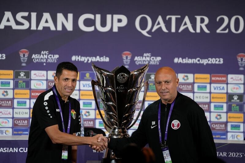 Jordan's head coach Lhoussanine Ammouta, left, and Qatar's head coach Bartolome Marquez shake hands in front of the Asian Cup trophy ahead of a press conference in Doha, Qatar, Friday, Feb.  9, 2024.  Jordan will play Qatar on Saturday for the soccer final of the Asian Cup.  (AP Photo / Thanassis Stavrakis)