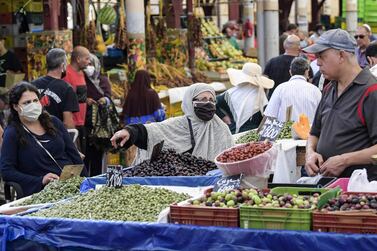 A mask-clad customer speaks with a fruit seller at the central market in Tunisia's capital Tunis. Moody's expects the country's economy to contract 6.5 per cent in the wake the Covid-19 crisis. AFP