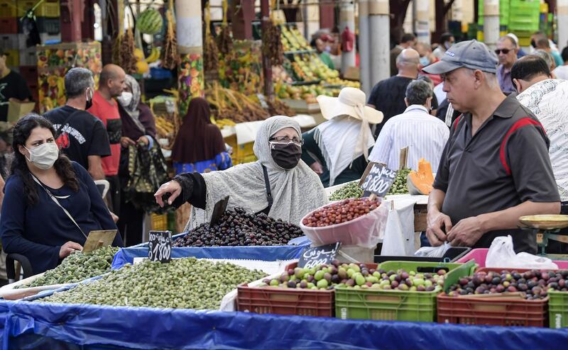 A mask-clad customer (COVID-19 coronavirus precaution) speaks with a fruit seller at his stall at the central market in Tunisia's capital Tunis on October 4, 2020. Tunisia's Prime Minister Hichem Mechichi announced late on October 3 a set of new measures aimed at curbing the spread of the novel coronavirus in the North African country, including a ban on all gatherings and stressing the importance of wearing face masks to limit the spike in new cases. / AFP / FETHI BELAID
