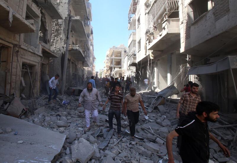 People walk among debris following a reported air strike by regime forces and their allies in Maaret Al-Noman in the southern Idlib province, on May 26, 2019. AFP