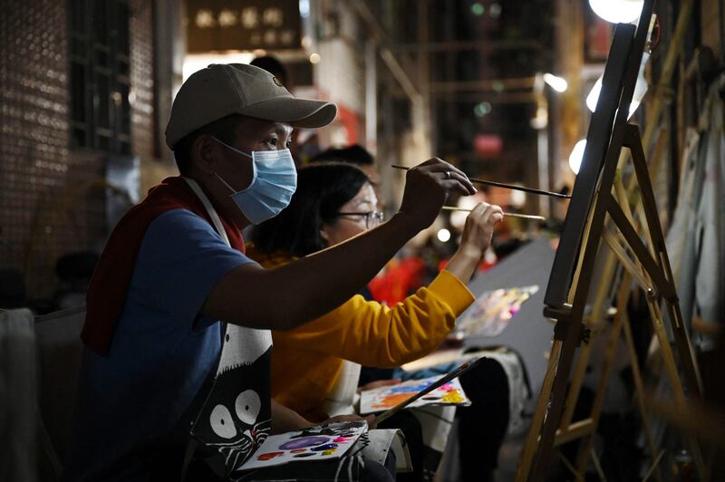 People painting in an alley in Dafen. Once known for churning out replicas, they are now selling original works worth thousands of dollars