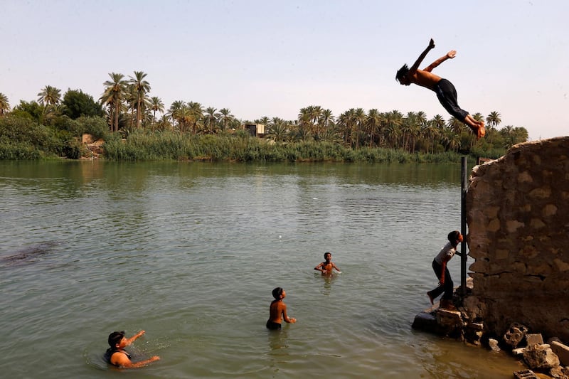 Iraqi youths dive into the Euphrates river to take a swim and cool off, during increased temperatures in the holy city of Najaf, Iraq July 14, 2020. Picture taken July 14, 2020.  REUTERS/Alaa Al-Marjani