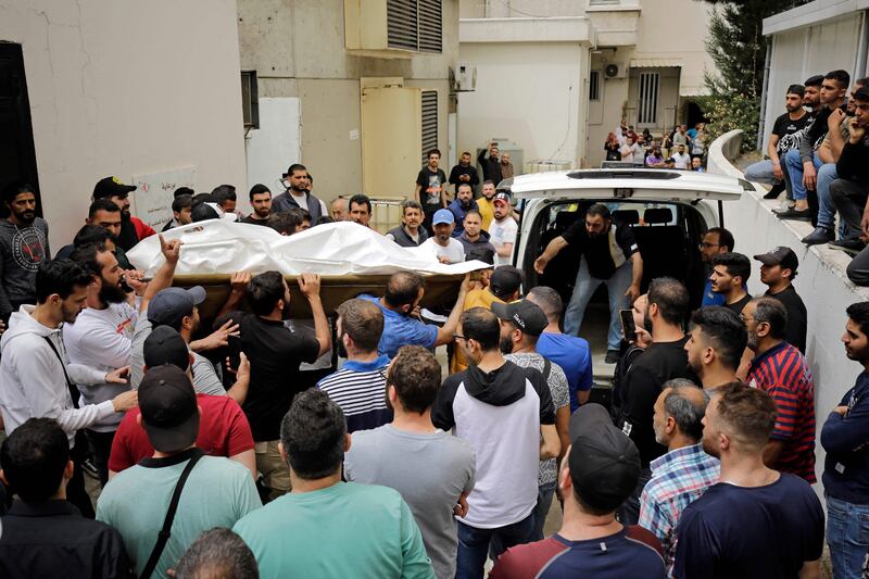 People gather at the morgue entrance of a hospital in Tripoli as others carry the corpse of one of the people who died when their boat capsized a day earlier off the coast of Libya. AFP