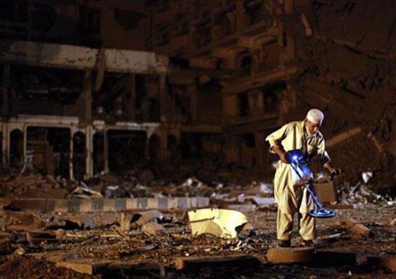 A man sorts through debris in the car park of the Pearl Continental Hotel in Peshawar, where suicide bombers detonated a lorry full of explosives.
