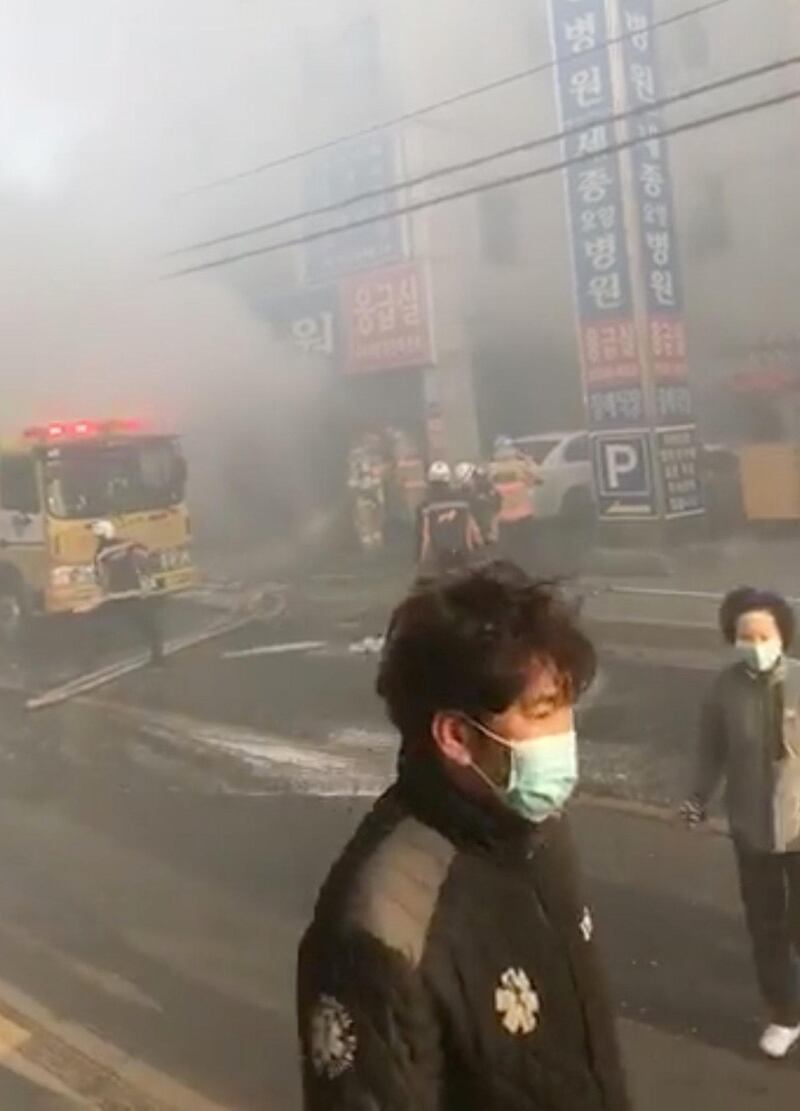 Emergency crews tend to the fire as pedestrians look on.  Woo Young Min via Reuters