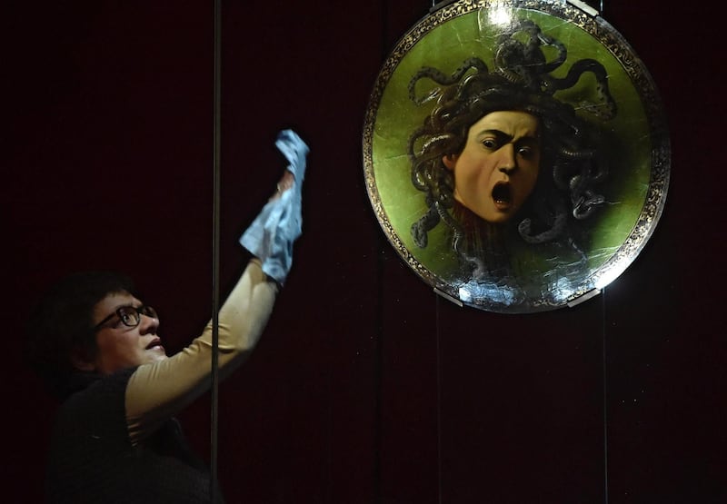 A woman cleans the glass display of the artwork 'Medusa' by Caravaggio at Galleria degli Uffizi  in Florence, Italy.  Maurizo Degl Innocenti / EPA