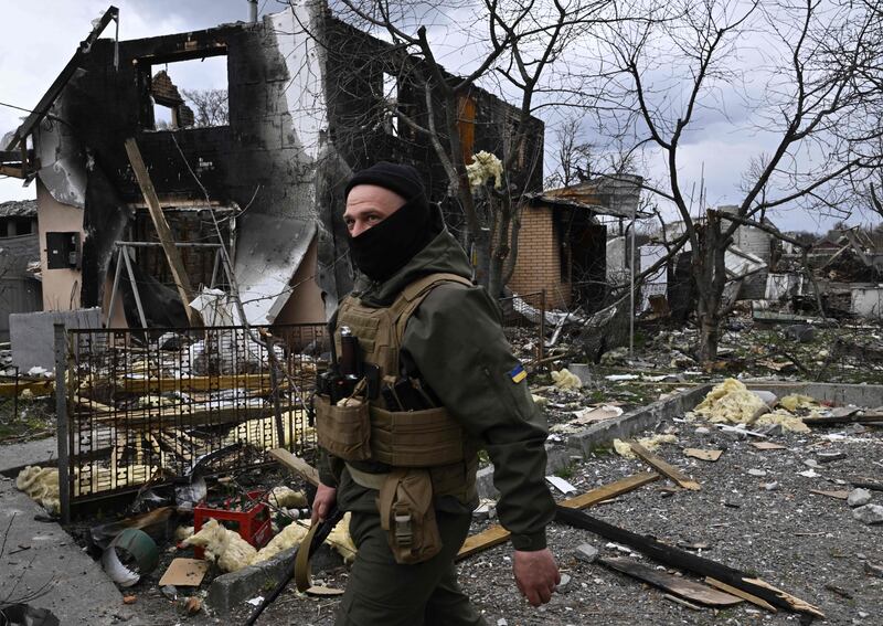 A Ukrainian fighter walks in front of a destroyed house in Bohdanivka village, north-east of Kyiv. AFP