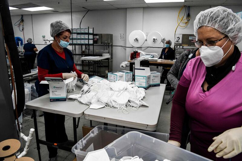 Employees work as they make respiratory masks in a family-owned medical equipment factory in north Miami, Florida on February 15, 2021.  A Florida company that saw an opportunity in the N95 mask shortage when the coronavirus pandemic began last year now has 30 million unsold masks because it can't find buyers in the United States. DemeTech, a Miami-based factory, blames lower prices from China, while a wholesale buyer thinks instead that the problem is that US buyers are wary of new manufacturers. / AFP / CHANDAN KHANNA
