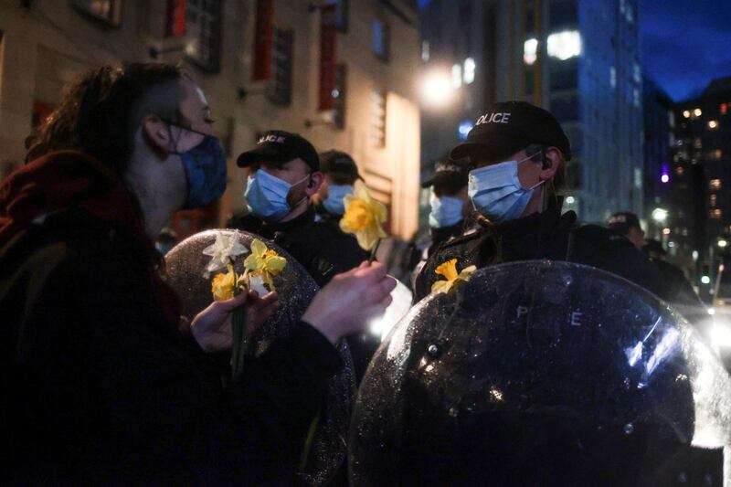 Police officers stand guard as a demonstrator offers a flower to police. Reuters